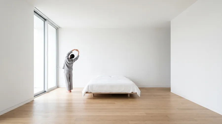 person doing a gentle morning stretch beside a window as part of a low-stimulation morning routine